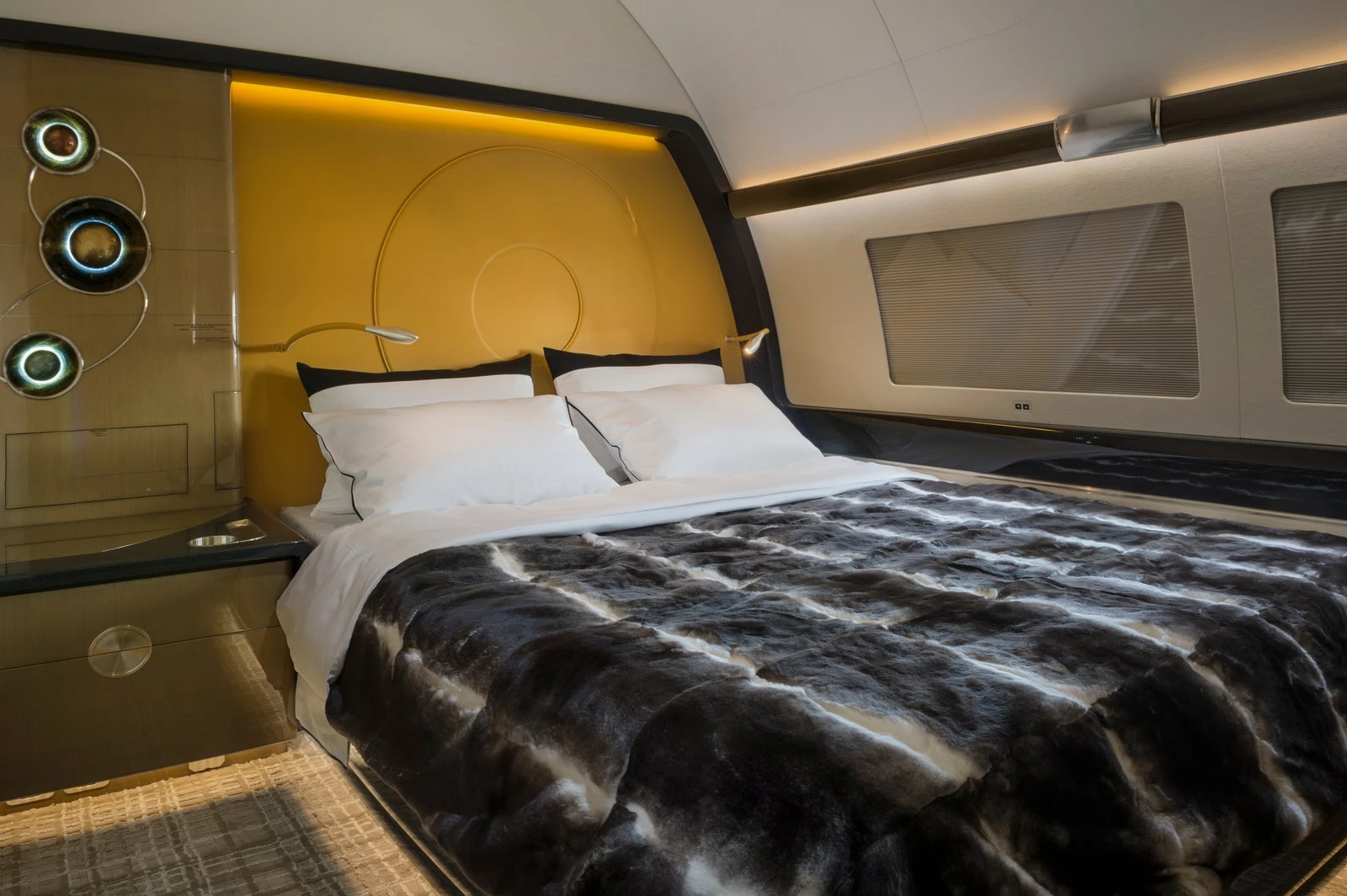 a bedroom with a yellow wall long windows and a bed covered in black and white fur