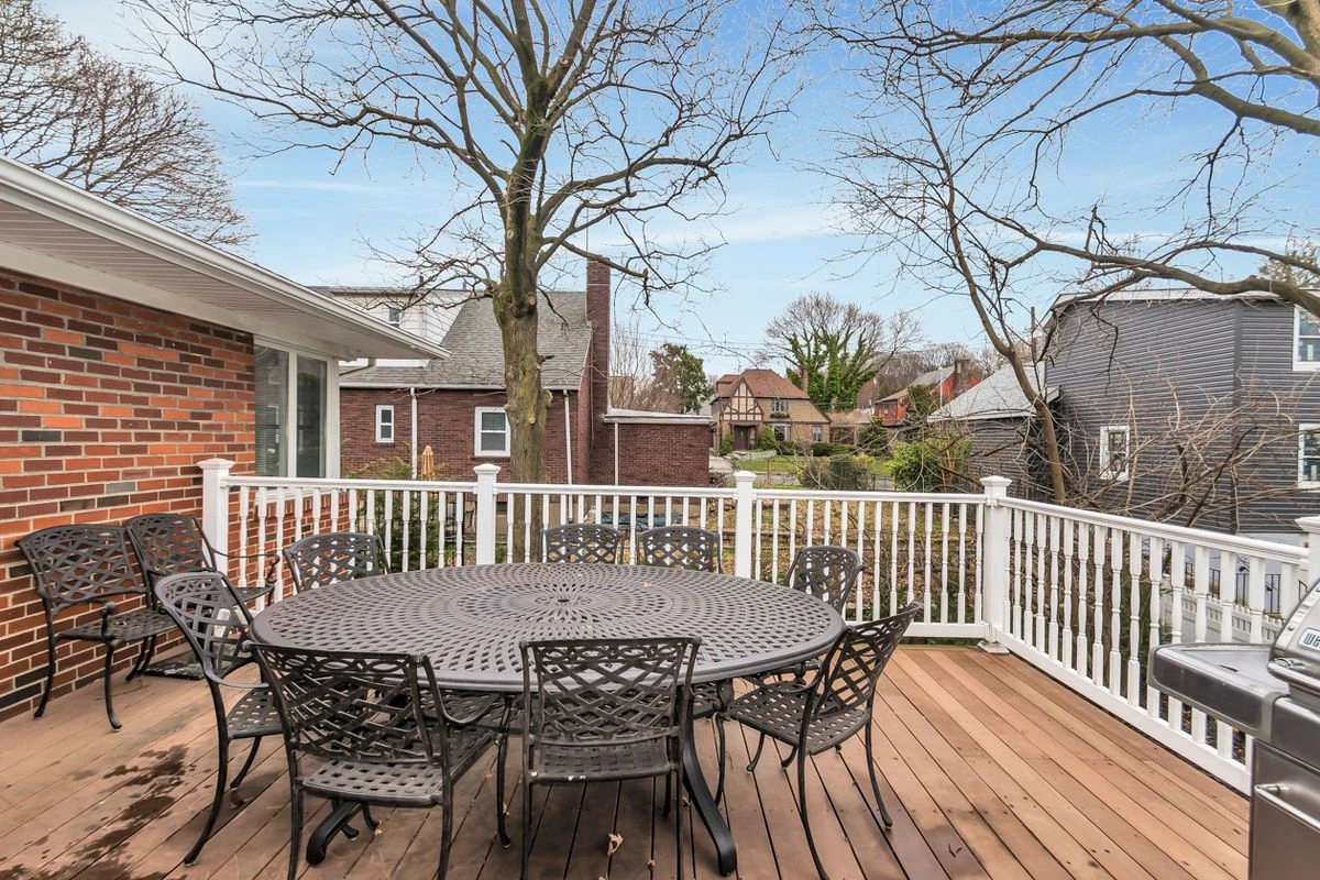 A wood deck with a round table, several chairs, and a barbecue grill.