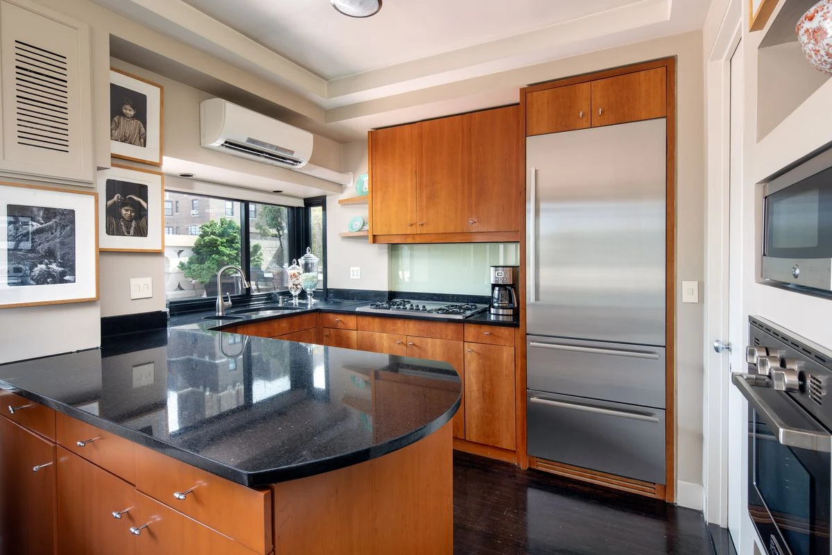 A kitchen with black countertops, wood cabinets, and stainless steel appliances.